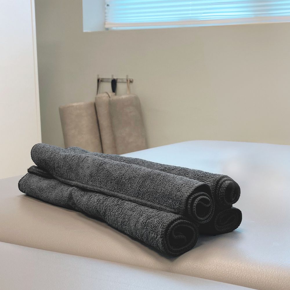 Tre håndklæder ligger sammenrullet på massage briks.